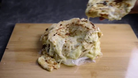 Video of Hand placing a pupusa on a stack of pupusas on a wooden board and da Stockbeeldmateriaal 221275327