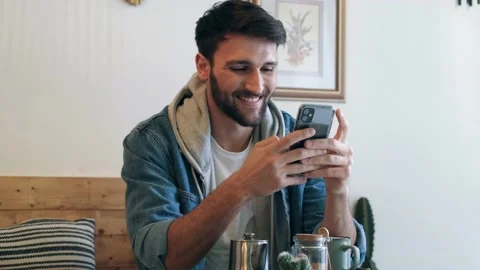 Video of handsome young man using his smartphone while drinking a cup o coffe 스톡 동영상 213293486