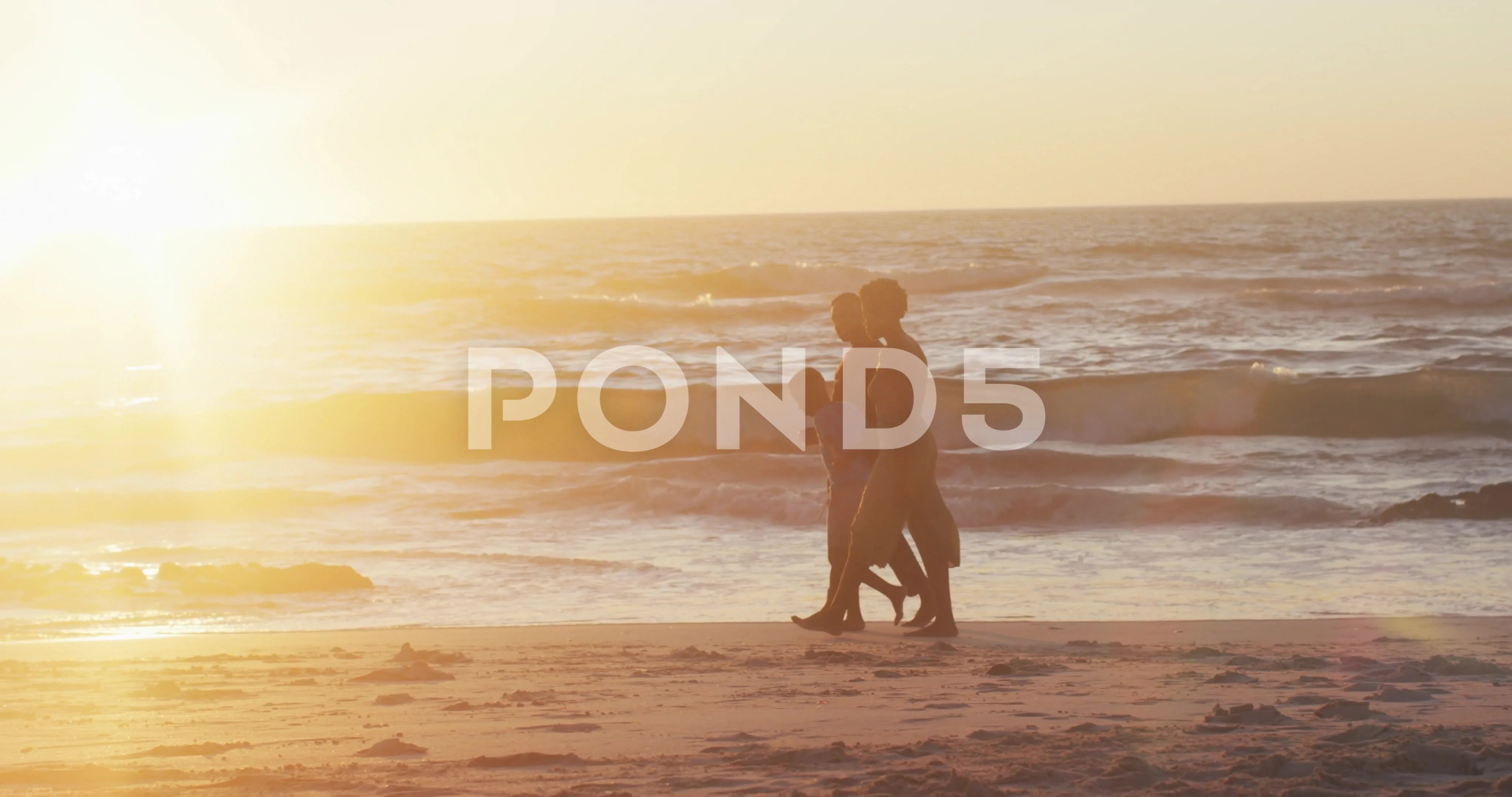 Video of happy african american family walking on beach at sunset