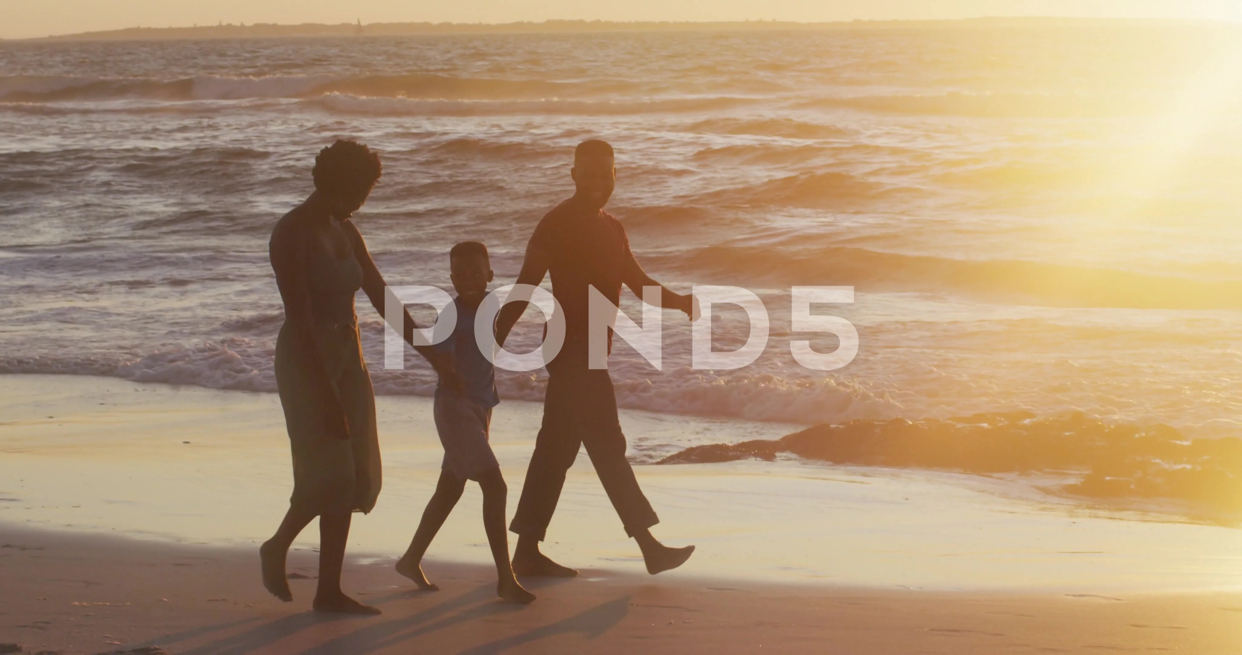 Video of happy african american family walking on beach at sunset