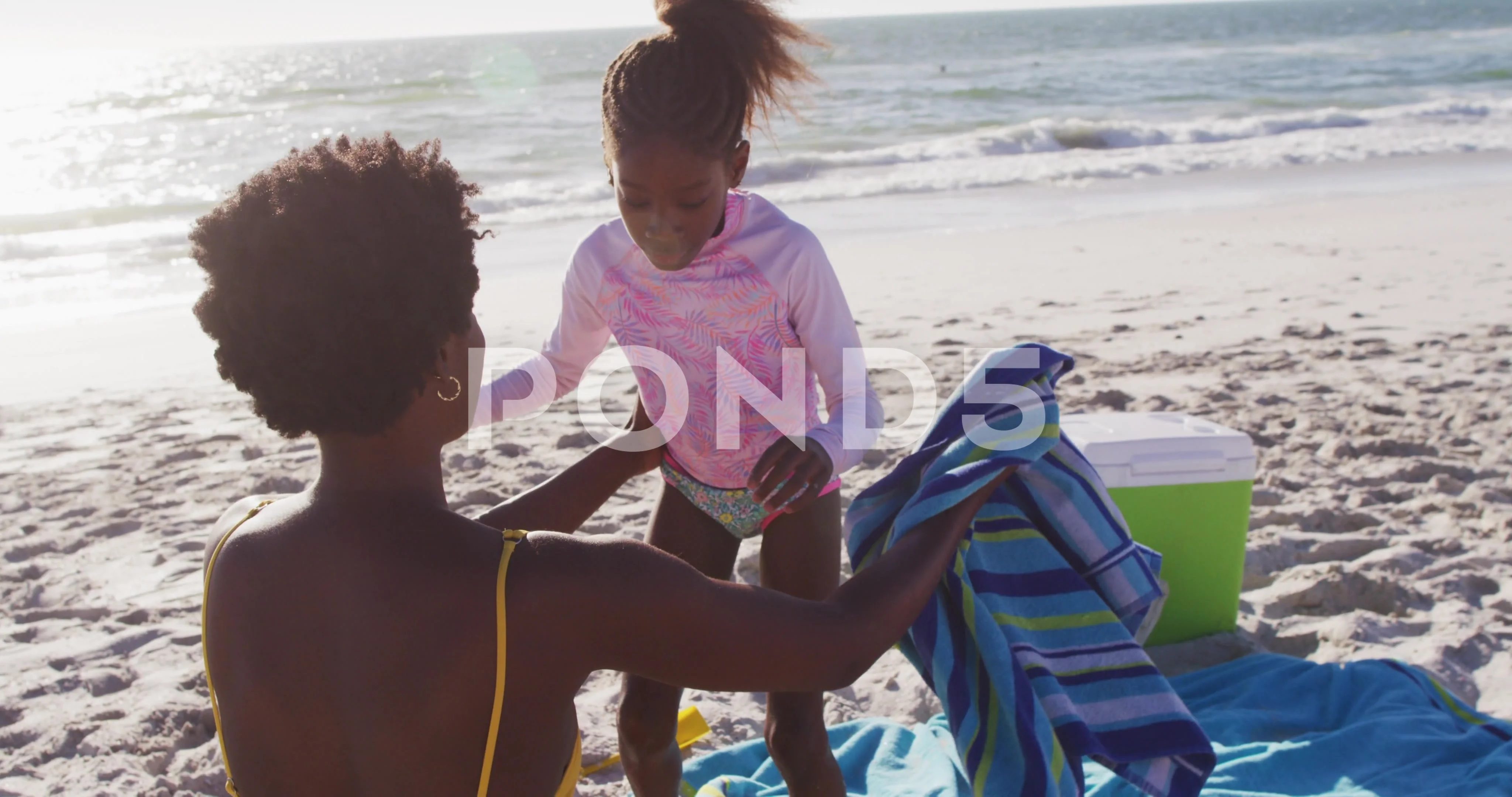 Video of happy african american mother and daughter hugging on beach