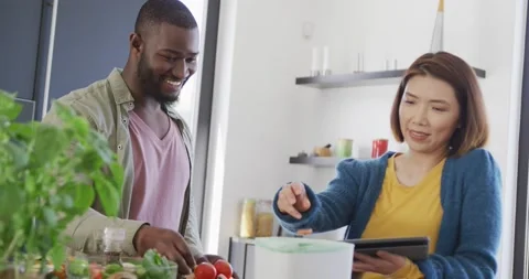 Video of happy diverse couple preparing food, using tablet and composting Stock Footage 219899397