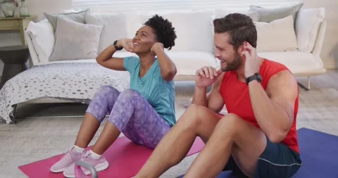 Video of happy diverse couple training together at home, doing sit ups Stock Footage 342110933