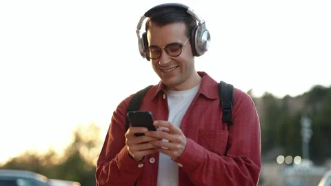 Video of happy man using smartphone while listening to music with headphone.. Video stock 303967684