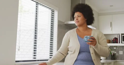 Video of happy plus size african american woman drinking coffee and using Stock Footage 340256377