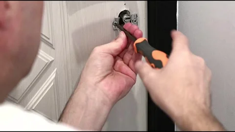 In the video, a locksmith adjusts the door handle door using a screwdriver Stock Footage 289543809