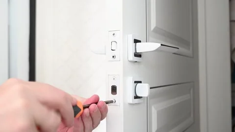 In the video, a locksmith adjusts the door lock on a door with a screwdriver Stock Footage 289543936
