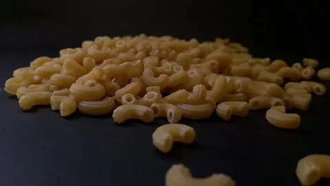 Video of macaroni food grains falling from top to bottom indoors on black backgr Stock Footage 324042254