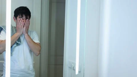 Video of a man brushing his teeth in his bathroom in front of the mirror Stock Footage 297666127