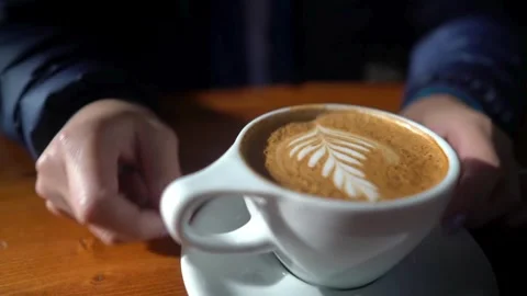 Video of a Man hands holding espresso coffee with latte art in a white mug. Vídeo Stock 334649064