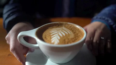 Video of a Man hands holding espresso coffee with latte art in a white mug. Stock Footage 334649092