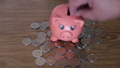 Video of a man inserting coins into a pink ceramic piggy to try to save for a Stock Footage 151555448