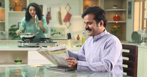 Video of  man reading newspaper at kitchen table while wife cooking in kitchen Stock Footage 255423927