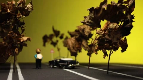 Video of a man sitting next to his broken, blue, retro car figurine in the mi Stock Footage 133493293