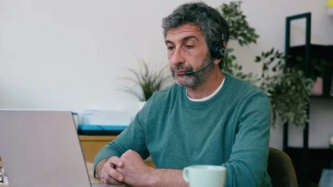Video of mature man doing a videocall with laptop while talking with earbud.. Stock Footage 340829301