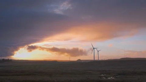 Video of moving clouds at sunset over a field with wind turbines to generate Stock Footage 230097802