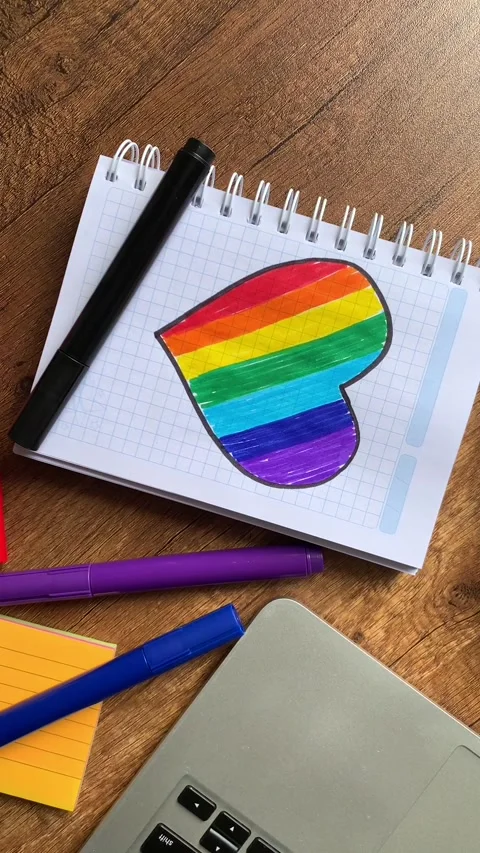 Video of notebook on wooden table with hand drawn LGBTQ+ heart. Stock Footage 262453453