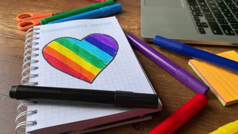 Video of notebook on wooden table with hand drawn LGBTQ+ heart. Stock Footage 262453696
