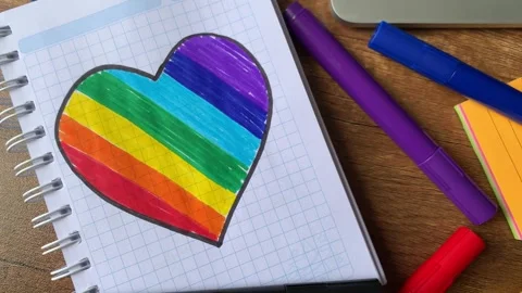Video of notebook on wooden table with hand drawn LGBTQ+ heart. Stock Footage 262453697