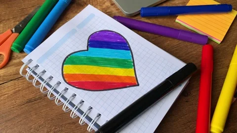 Video of notebook on wooden table with hand drawn LGBTQ+ heart. Stock Footage 262453701