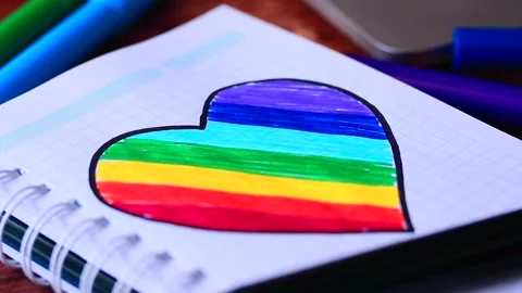 Video of notebook on wooden table with hand drawn LGBTQ+ heart. Stock Footage 262598482
