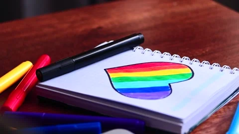 Video of notebook on wooden table with hand drawn LGBTQ+ heart. Stock Footage 262598484