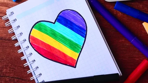 Video of notebook on wooden table with hand drawn LGBTQ+ heart. Stock Footage 262598497