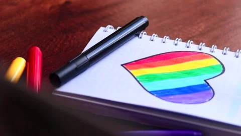 Video of notebook on wooden table with hand drawn LGBTQ+ heart. Stock Footage 262598498