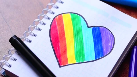 Video of notebook on wooden table with hand drawn LGBTQ+ heart. Stock Footage 262598606
