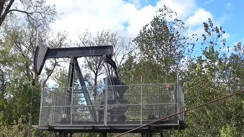Video of an oil pump jack pumping oil from a small oil well Stock Footage 81403162