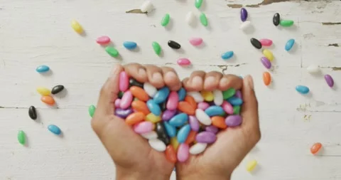Video of overhead view of man holding multi coloured sweets over white rustic Stock Footage 340008071