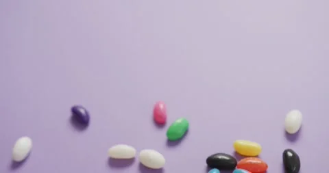 Video of overhead view of multi coloured sweets with copy space over purple Stock Footage 340963871