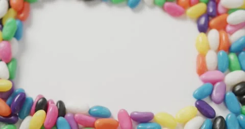 Video of overhead view of multi coloured sweets with copy space over white Stock Footage 341088562