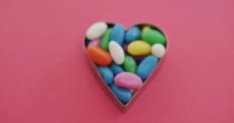 Video of overhead view of multi coloured sweets in heart shape over red Vídeo Stock 344330229