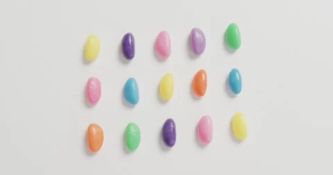 Video of overhead view of rows of multi coloured sweets over white background Stock Footage 339319993