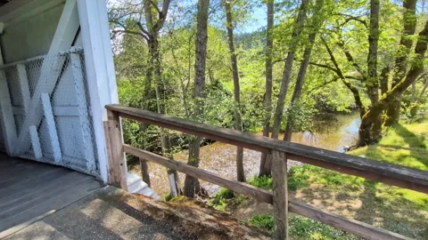 Video panning from a covered pedestrian bridge to a rushing river Stock Footage 334965632