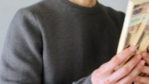 Video of a person looking back and holding a stack of bills Stock Footage 324543737