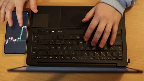 Video of a person using a laptop to check cryptocurrency charts while typing Stock Footage 322095894
