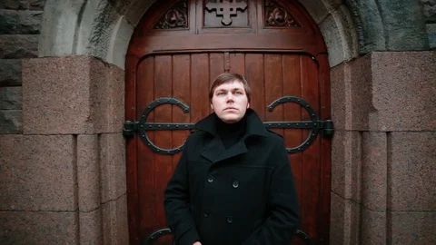 Video Portrait of a young man dressed in a black coat on a stained-glass door Stock Footage 127992196