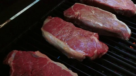 Video of putting raw steaks on the grill in real slow motion Stock Footage 86039391
