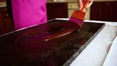 Video recording of the process of tempering melted liquid chocolate on a marble  Stock Footage 154555894