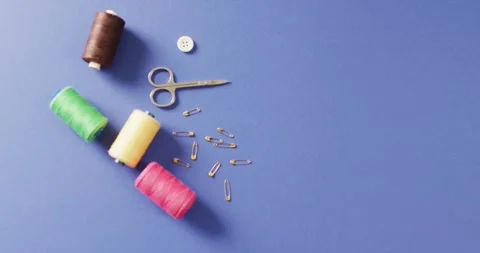 Video of scissors, safety pins, a button and reels of thread on blue background Stock Footage 331307097