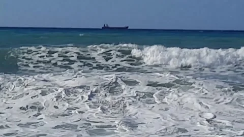 Video of ship on Horizont and foaming waves crashing noisily on a sandy beach of Stock Footage 289478861