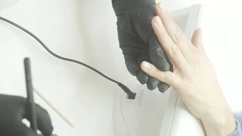 This video showcases a nail technician in black gloves working meticulously on a Stock Footage 305647080