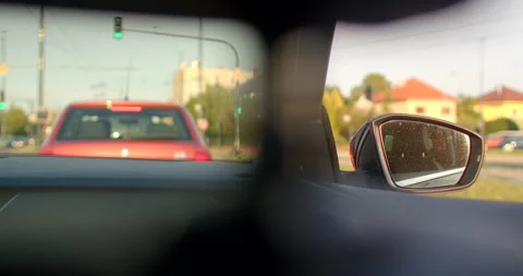The video shows a car driving through the city, focusing on its mirror Stock Footage 314347376