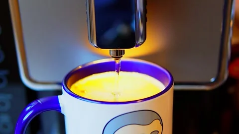 The video shows a coffee machine pouring coffee into a blue and white mug. Stock Footage 299075324