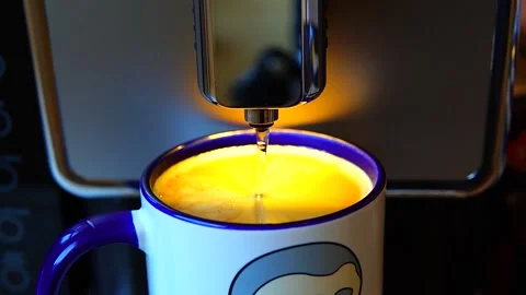 The video shows a coffee machine pouring coffee into a blue and white mug. Stock Footage 299076966
