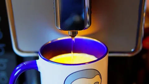 The video shows a coffee machine pouring coffee into a blue and white mug. Stock Footage 299077919