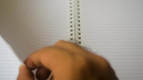 This video shows a hand flipping through the blank pages of a spiral notebo.. Stock Footage 332913866