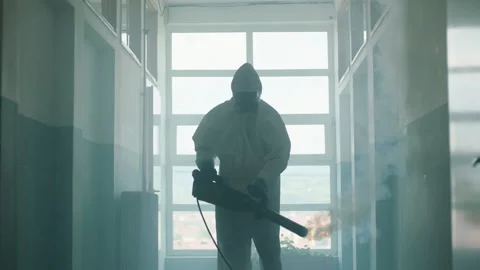 This video shows a man in protective overalls sanitizing a school corridor, s Stock-Footage 137758161
